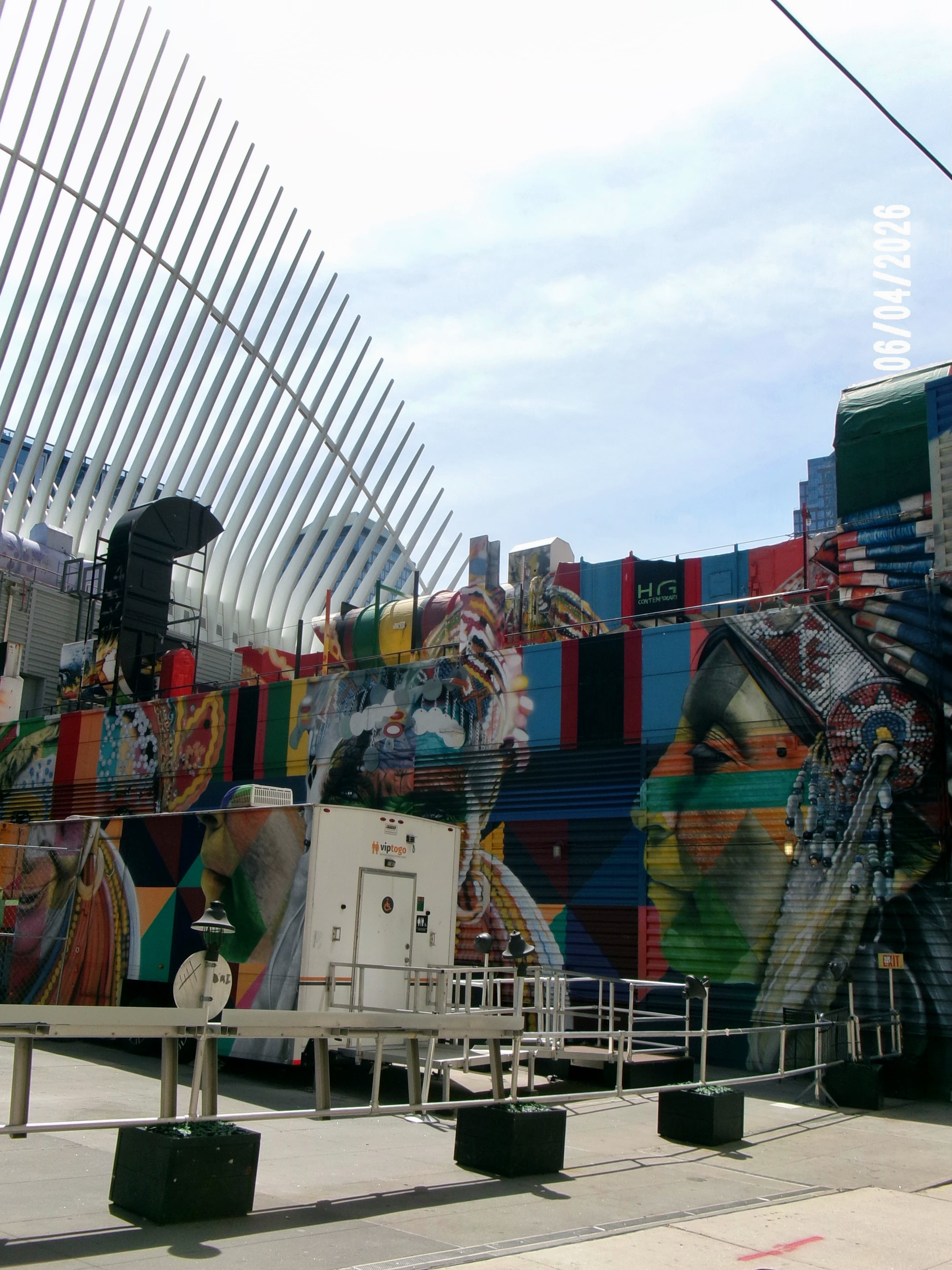 The white ribbed wings of the Oculus in Lower Manhattan above a building covered in a colorful mural